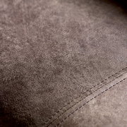 Nahaufnahme der Textur eines braunen Ledersofas mit sichtbaren Nähten, von oben betrachtet.