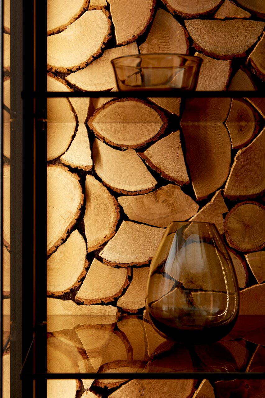 Nahaufnahme eines Regals mit dekorativem Kaminholz-Rückwandakzent und Glasvasen, seitliche Perspektive.