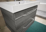 Moderne Waschtischlösung mit grauem Holzfinish und zwei Schubladen, seitliche Perspektive