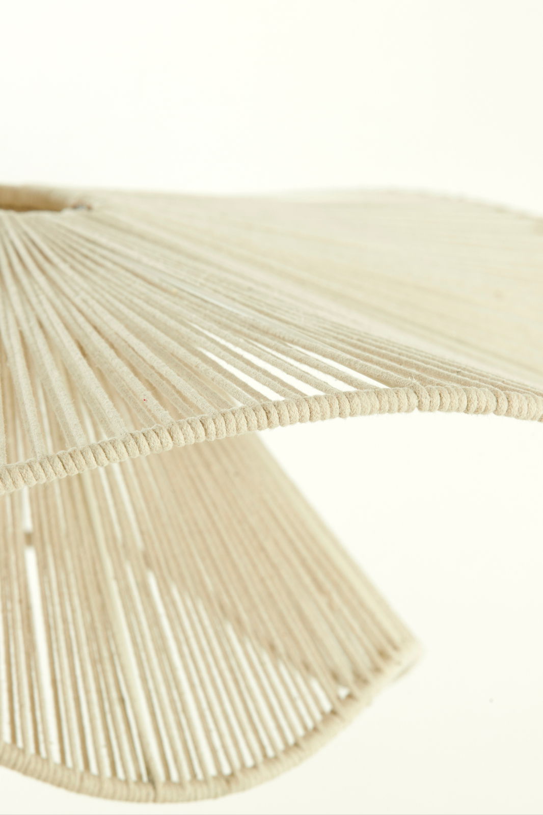 Nahaufnahme einer Hängeleuchte mit einem Schirm aus beigen Fäden, die in einem gleichmäßigen Muster angeordnet sind. Perspektive von unten.