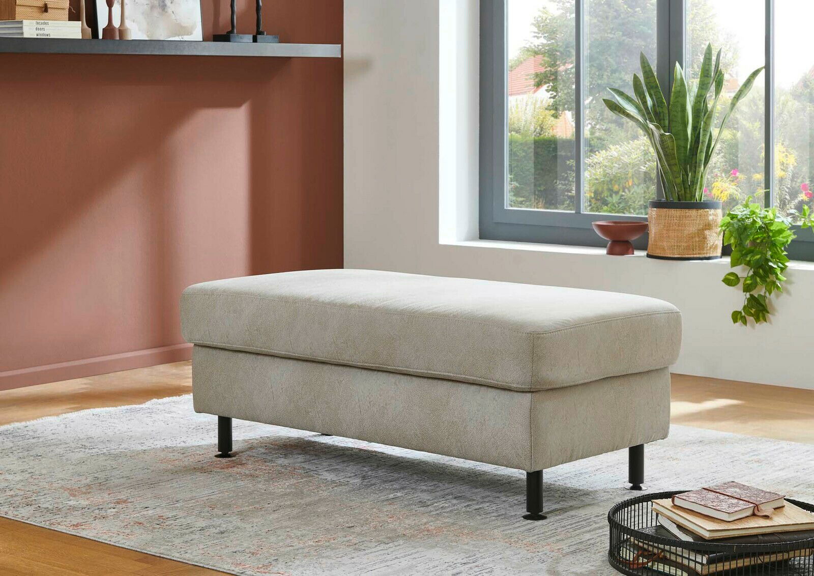 XXL Hocker in einem modernen Wohnzimmer, seitliche Perspektive, mit Pflanzen und Büchern im Hintergrund.