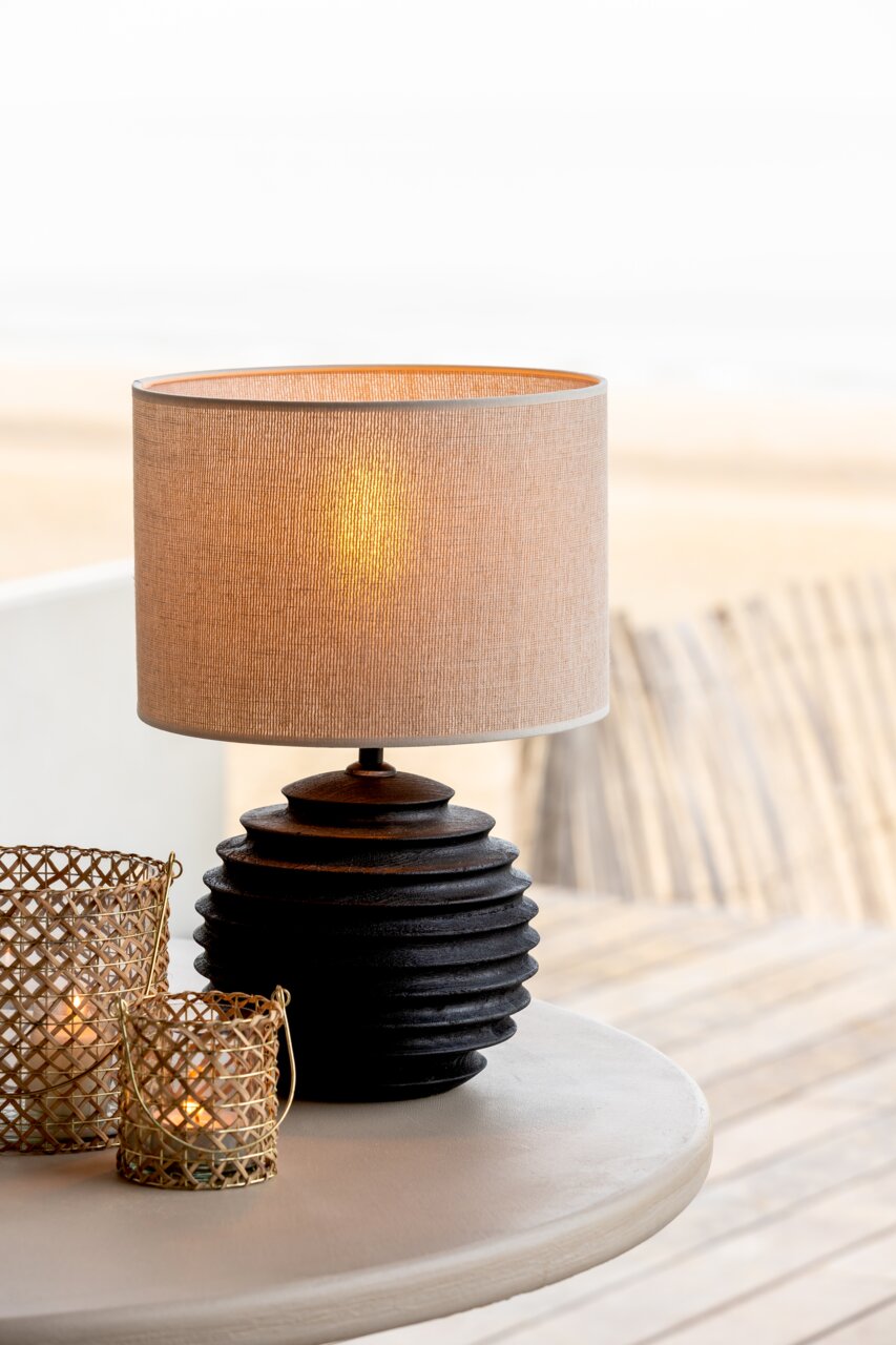 Moderner Lampenschirm mit strukturiertem, dunklem Sockel auf einem Tisch, seitliche Perspektive.