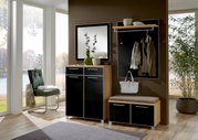 Modernes Garderoben-Set in einem hellen Raum mit großen Fenstern, bestehend aus einem Spiegel, einer Kommode, einer Sitzbank und einer Wandgarderobe mit Haken und Ablage. Perspektive von vorne.