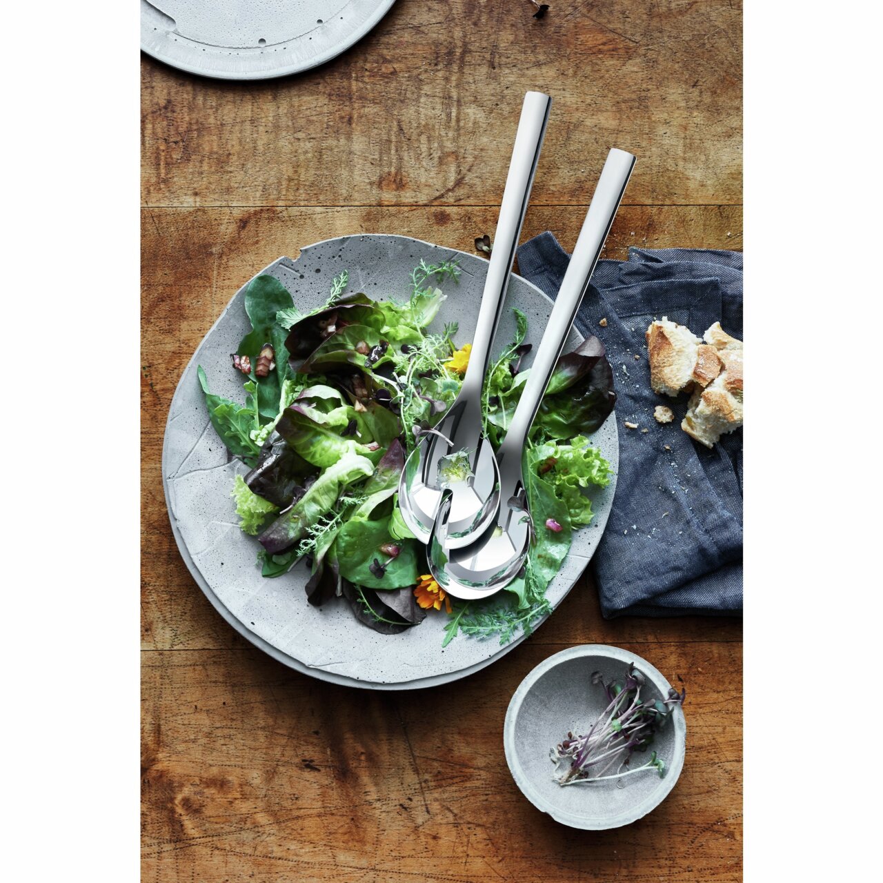 Salatbesteck NUOVA 30cm aus Edelstahl, auf einem Salatteller mit frischem Salat, von oben fotografiert.