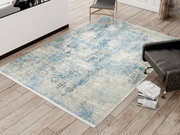 Designer Teppich in Blau- und Beigetönen auf einem Holzboden, fotografiert aus der Vogelperspektive.