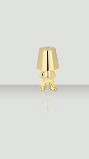 Goldene Akku-Tischleuchte in Form einer stilisierten Figur, frontal abgebildet.