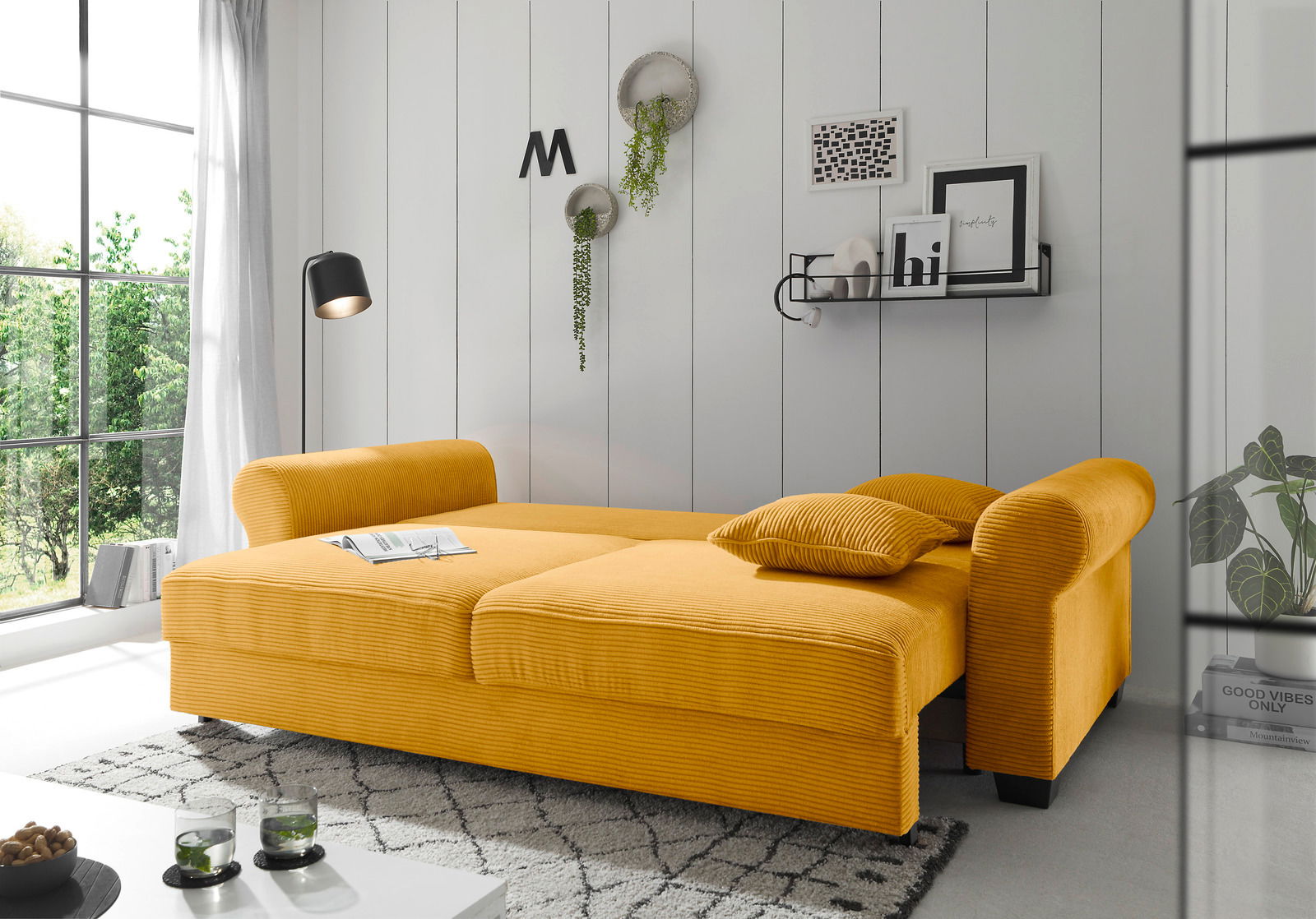 Gelbes Funktionssofa in einem modernen Wohnzimmer, seitliche Perspektive, mit Kissen und dekorativen Elementen an der Wand.