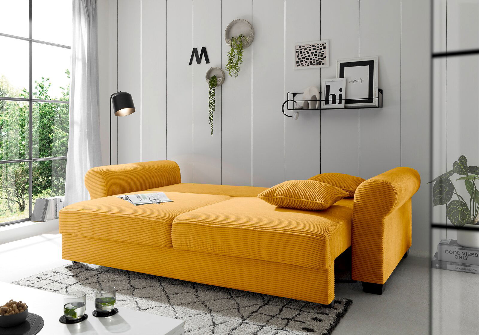 Gelbes Funktionssofa in einem modernen Wohnzimmer, seitliche Perspektive, mit Kissen und dekorativen Elementen an der Wand.