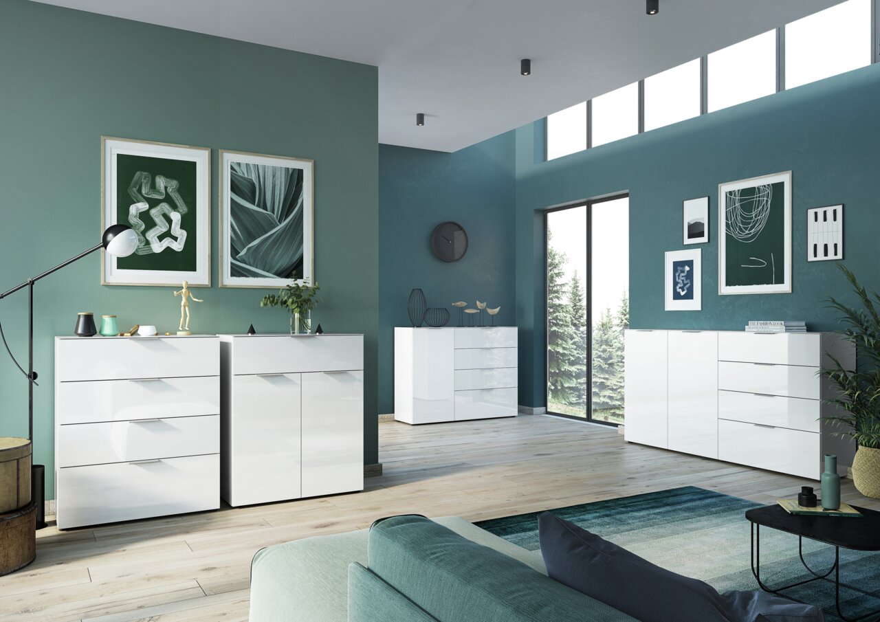 Modernes weißes Sideboard in einem stilvoll eingerichteten Wohnzimmer mit grünen Wänden und großen Fenstern, seitliche Perspektive.