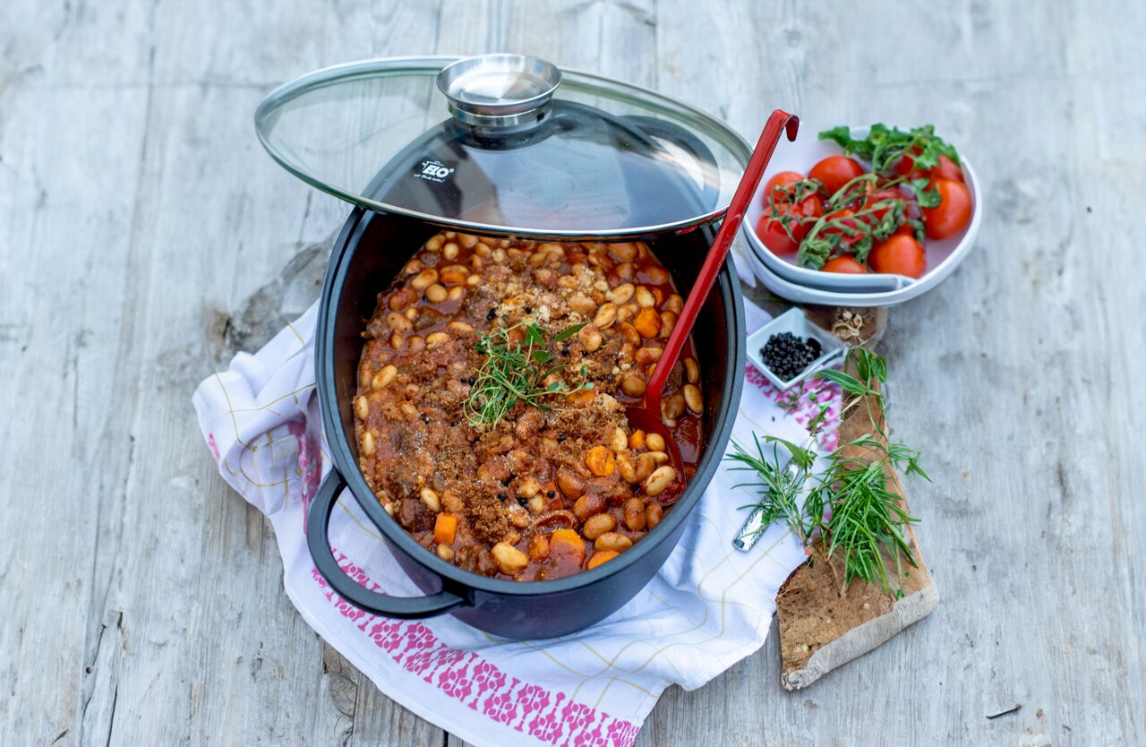Elo Bräter oval ALUCAST ELO Alucast Bräter oval ELODUR mit Glasdeckel, gefüllt mit einem Eintopf aus Bohnen und Gemüse, von oben fotografiert.