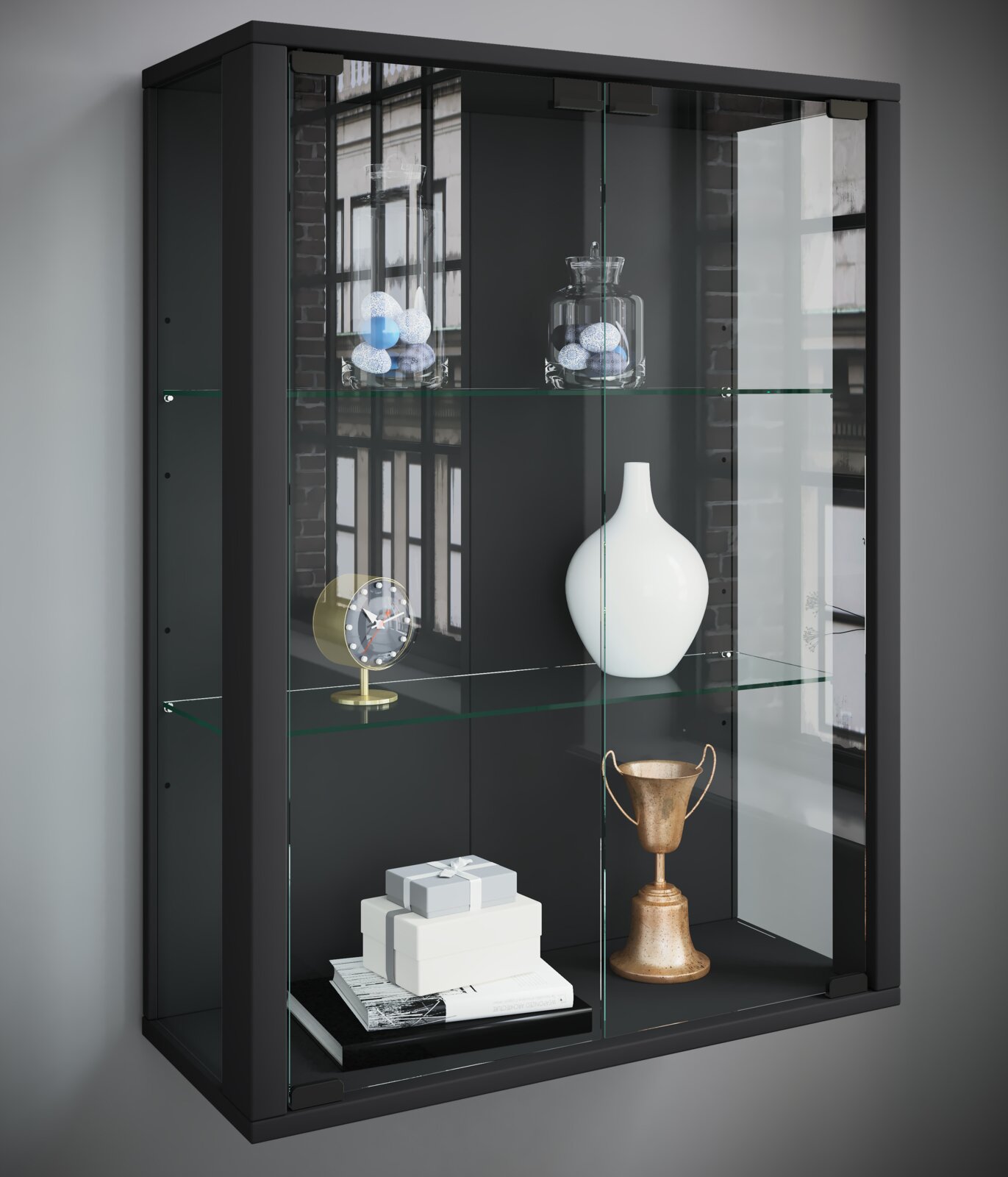 Schwarze Glasvitrine mit Glasböden und zwei Glastüren, bestückt mit Deko (Vase, Uhr, Pokal, Geschenkboxen), in schräger Frontansicht von links.