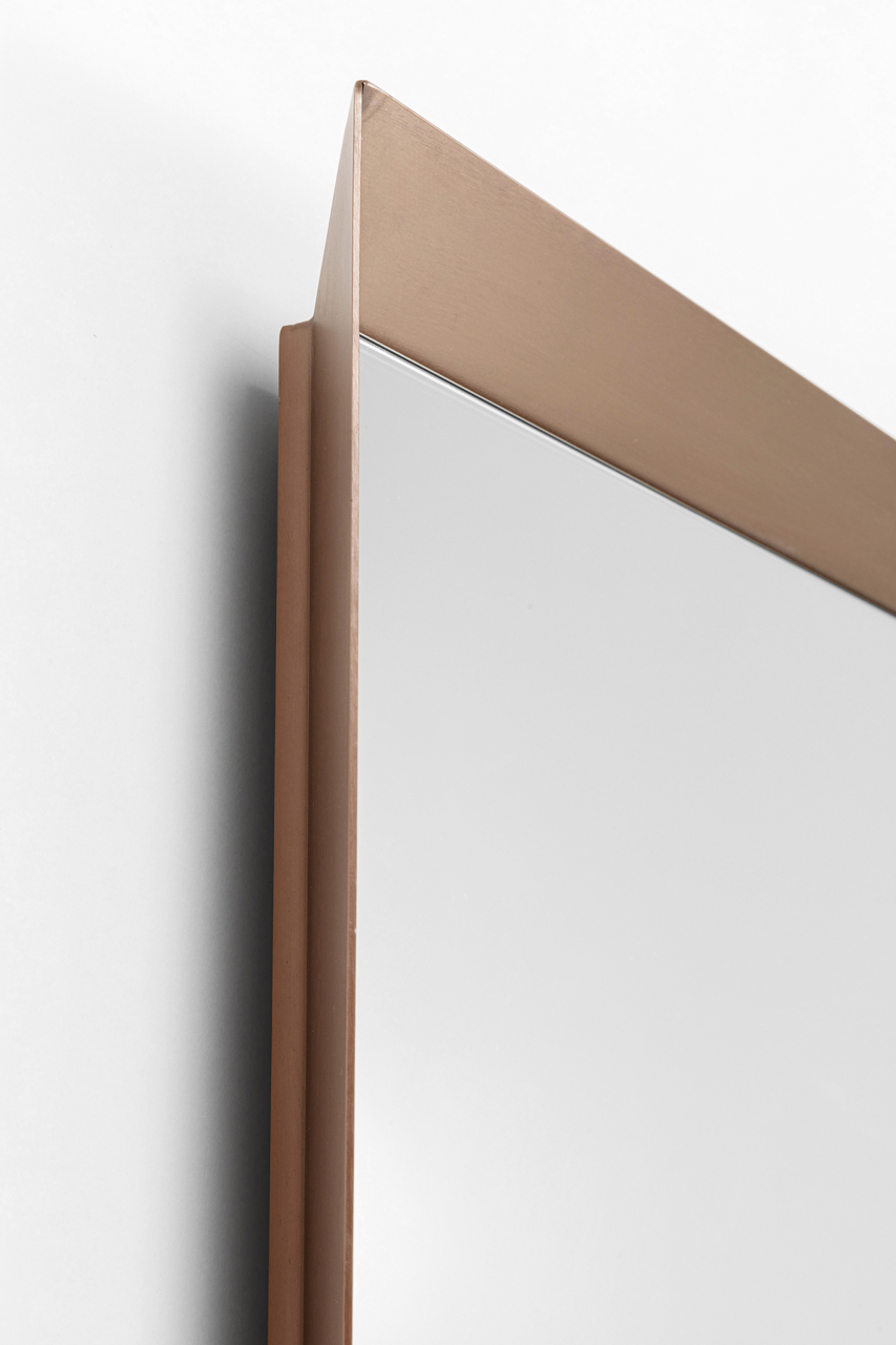 Nahaufnahme eines Wandspiegels mit einem eleganten, bronzefarbenen Rahmen, seitliche Perspektive.