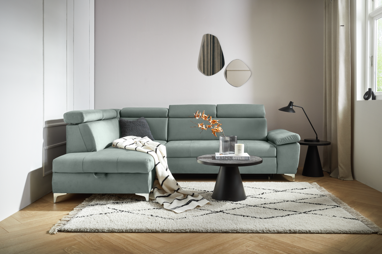 Moderne Rundecke in L-Form in einem hellen Wohnzimmer, mit einem grauen Stoffbezug und verstellbaren Kopfstützen, von vorne betrachtet.