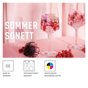 Zwei elegante Weingläser mit floralen Motiven und Beeren, auf einem rosa Hintergrund, aus der Perspektive leicht von oben betrachtet.