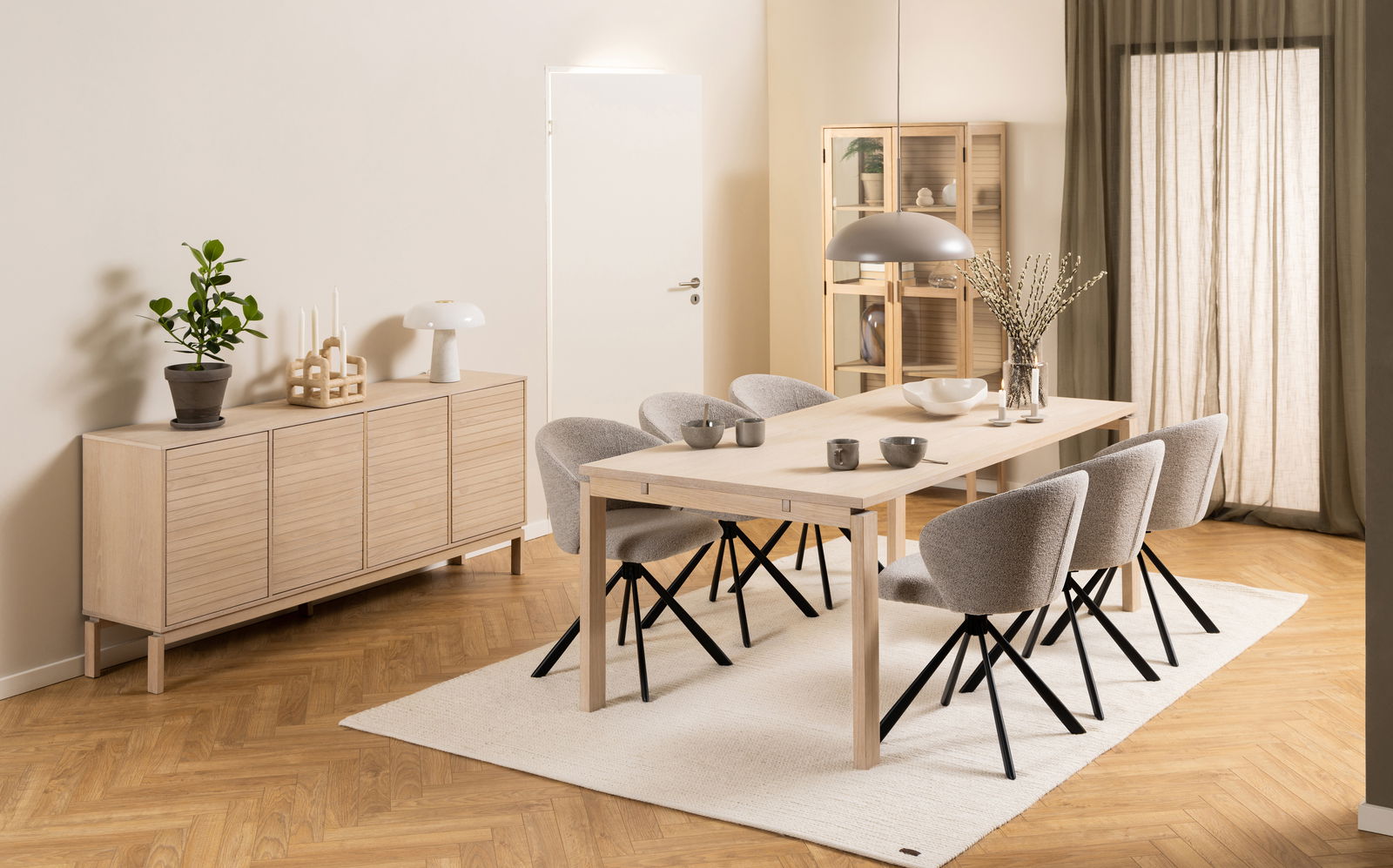 Moderner Esstisch aus hellem Holz mit sechs grauen Stühlen, seitliche Perspektive.