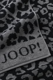 Graues Handtuch mit schwarzem Leopardenmuster und dem Schriftzug 'JOOP!' in Nahaufnahme.