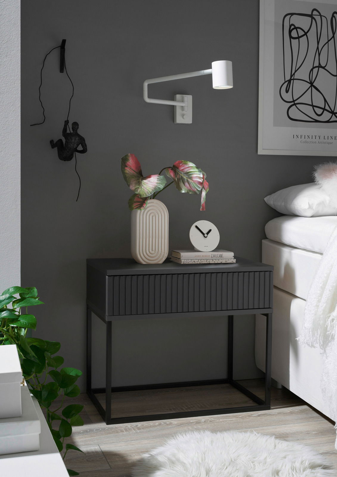 Moderne Nachtkommode in dunklem Design mit dekorativer Vase und Uhr, seitliche Perspektive