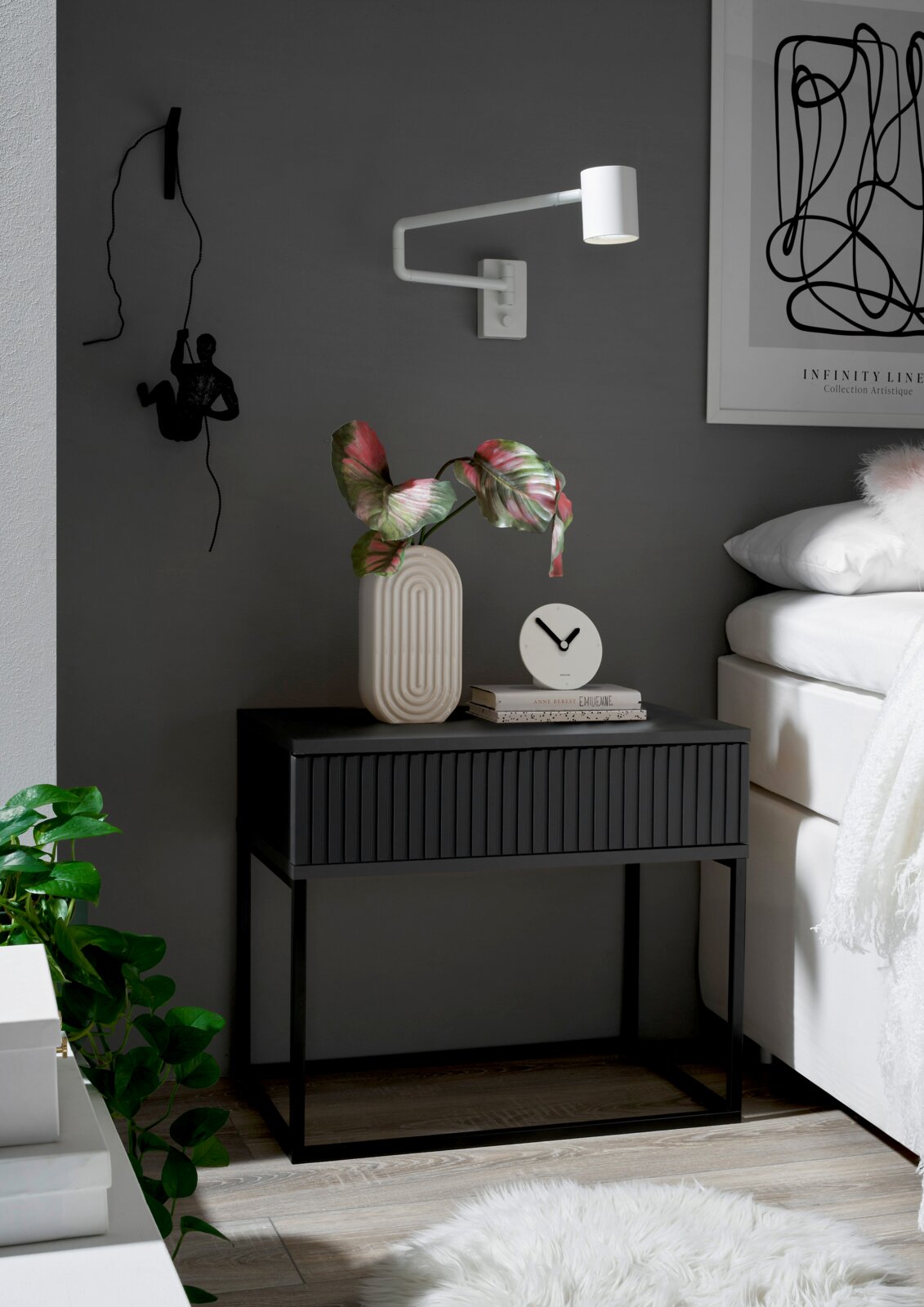 Moderne Nachtkommode in dunklem Design mit dekorativer Vase und Uhr, seitliche Perspektive