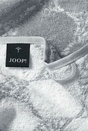 Nahaufnahme eines weichen, grauen Gästetuchs mit einem schwarzen Etikett, auf dem 'JOOP!' steht.