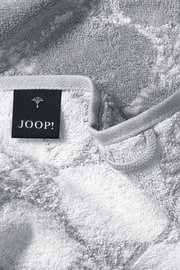 Nahaufnahme eines weichen, grauen Gästetuchs mit einem schwarzen Etikett, auf dem 'JOOP!' steht.