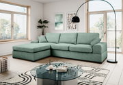Mintgrünes L-förmiges Ecksofa mit Ottomane links und drei Sitzkissen in modernem Wohnzimmer, fotografiert in frontaler leicht schräger Perspektive.