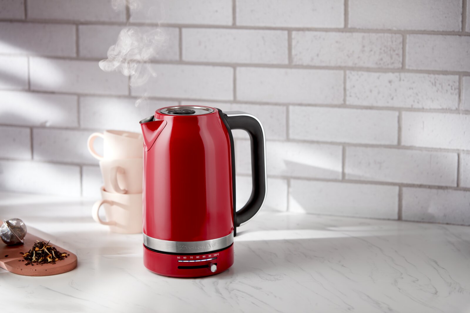 KitchenAid Wasserkocher 1,7l 5KEK1701EER Roter Wasserkocher mit 1,7 Liter Fassungsvermögen, seitliche Perspektive, auf einer Küchenarbeitsplatte mit dampfendem Ausguss.