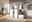 Moderne Garderobenkombination in einem hellen Raum mit weißem Hochglanz-Finish, bestehend aus einem Schrank mit mehreren Fächern, einer Sitzbank mit Stauraum und einer Wandgarderobe mit Haken und Ablage. Perspektive von vorne.