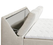 Nahaufnahme eines Boxspringbetts mit geöffnetem Stauraum im Kopfteil, seitliche Perspektive