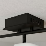 Schwarze Deckenhalterung aus Metall mit Langlöchern und Schraube, Detailansicht aus Untersicht in leichter Schrägperspektive an einer hellen Decke montiert.