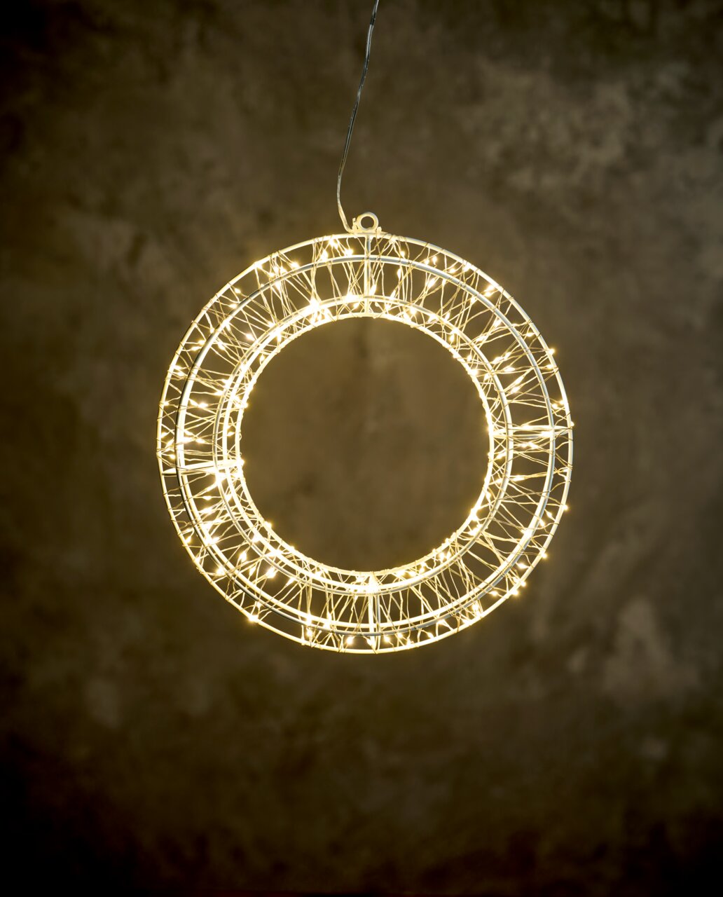 Een verlichte LED-krans met een diameter van 30 cm, gezien vanaf de voorkant, hangend tegen een donkere achtergrond.