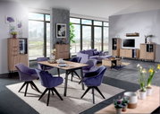 Moderne woonkamer met een eettafel en stoelen in het midden, omringd door vitrinekasten, een tv-kast en een salontafel in een lichte, open ruimte met grote ramen. Aanzicht van voren.