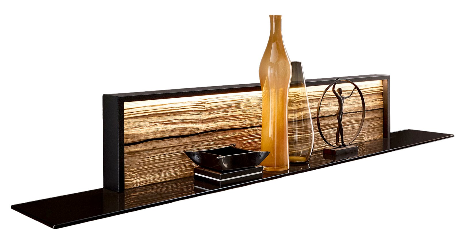 Moderne wandplank met een zwart schap en een verlicht houten paneel, versierd met glazen vazen, een schaal en een beeldje, gefotografeerd van voren in een licht zijdelings perspectief.