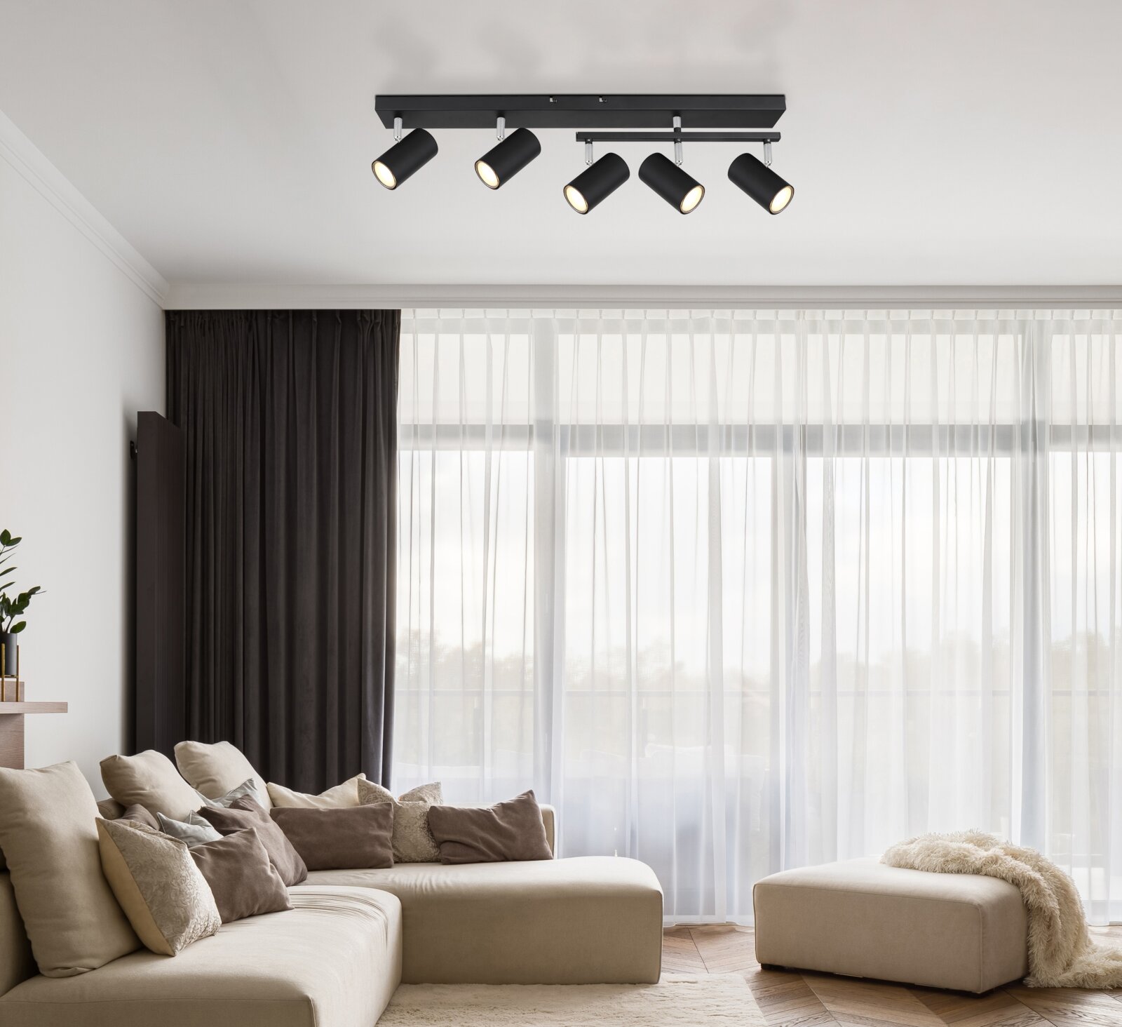 Moderner schwarzer Deckenstrahler mit fünf verstellbaren Spots in einem stilvollen Wohnzimmer, Perspektive von unten.
