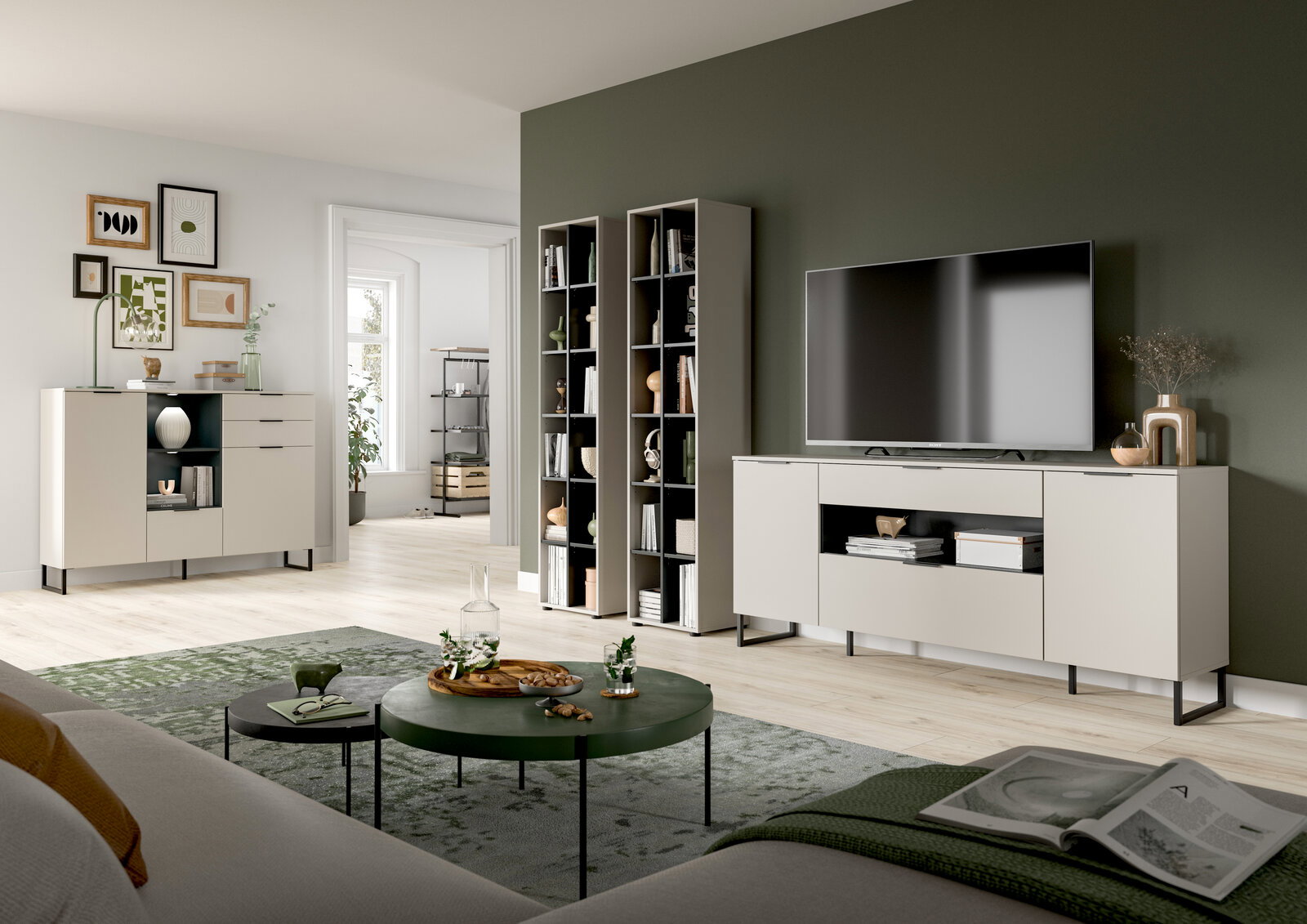 Modernes Wohnzimmer-Set mit hellen Sideboards und hohen Regalen vor olivgrüner Akzentwand, TV auf Lowboard, runde Couchtische auf Teppich; Perspektive: frontale Weitwinkelansicht aus leicht erhöhter Augenhöhe.