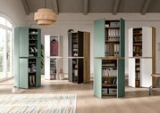 Moderne Hochschränke mit geöffneten Türen in Grün, Weiß und Holzoptik, teils als Schuh- und Kleiderschrank sowie Regal genutzt, in hellem Wohnraum; Perspektive: frontale, leicht weitwinklige Raumansicht.
