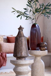 Windlicht aus Metall mit filigranem Muster, auf einem dekorativen Tisch stehend, seitliche Perspektive