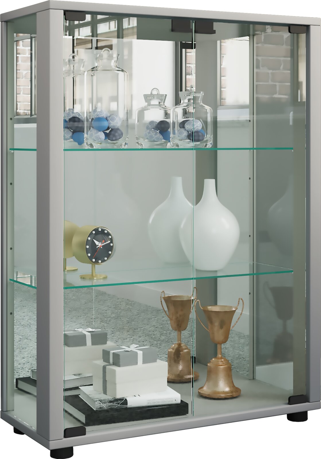 Graue Glasvitrine mit zwei Glasböden und Schiebetüren, befüllt mit Dekogläsern, weißen Vasen, Uhr und Pokalen, Ansicht schräg von vorne