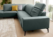 Hoekbank in een modern ontwerp met blauwe bekleding, gele en grijze kussens, op een lichte houten vloer en met uitzicht op een raam op de achtergrond.