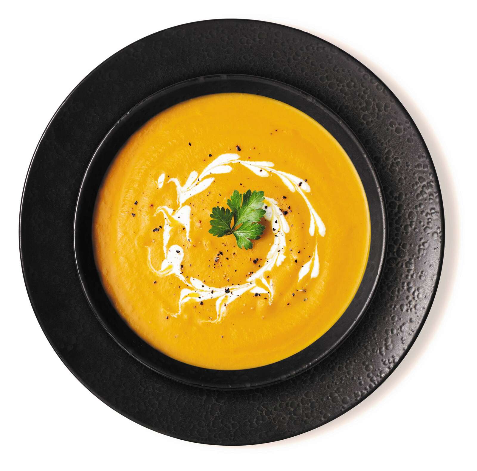 Ritzenhoff & Breker Tafelservice 8-tlg. KITWE Schwarzer Teller mit Suppenschale, gefüllt mit cremiger Kürbissuppe, dekoriert mit Sahne und Petersilie, aus der Vogelperspektive.