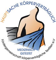 Logo der Fördergemeinschaft körperverträgliche Textilien e.V. mit der Aufschrift 'Hauptsache körperverträglich' und 'Medizinisch getestet', zeigt eine stilisierte Person mit einem Tuch um die Schultern, Vorderansicht.