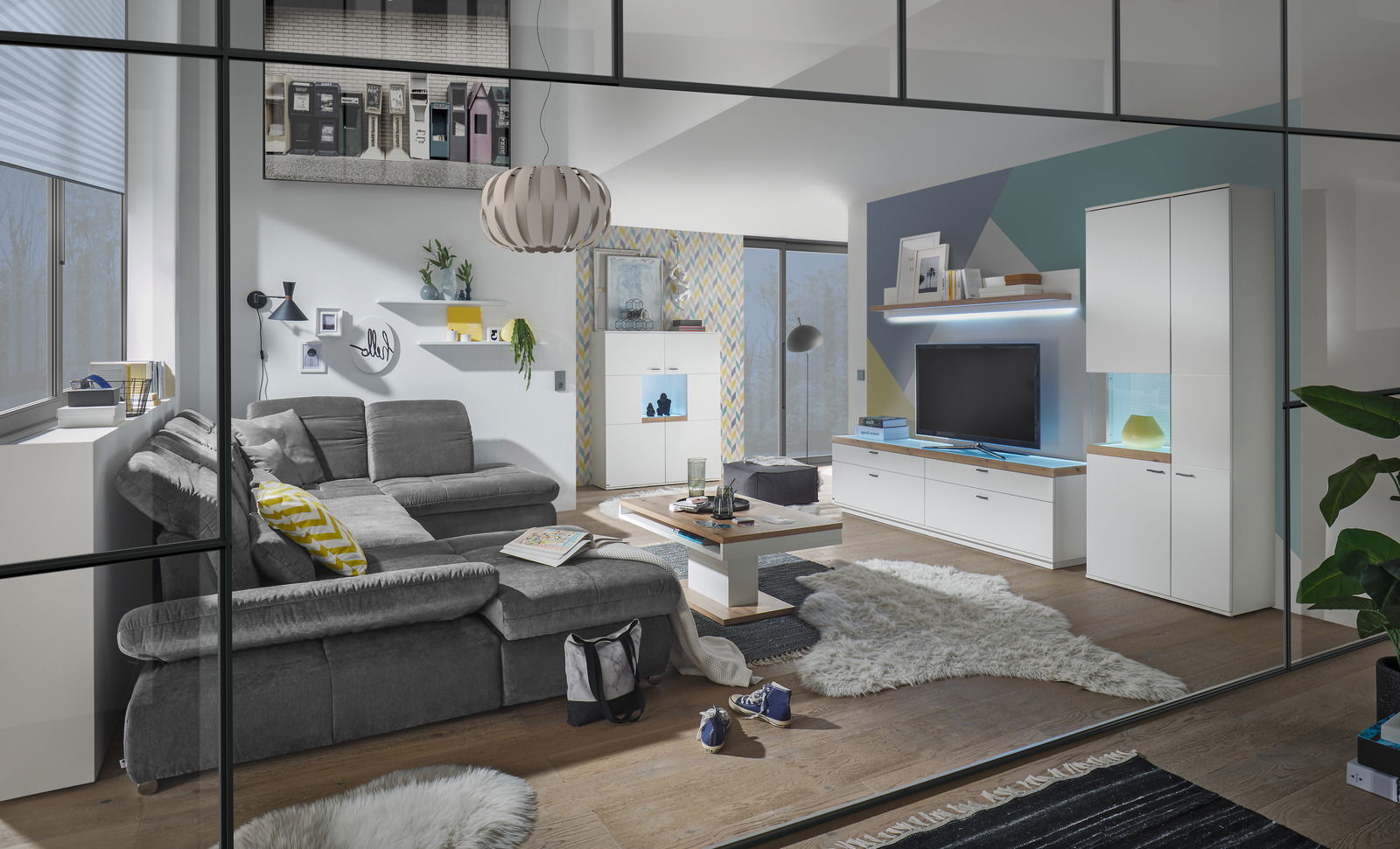 Set one by Musterring Vitrine Glasausschnitt links SET ONE LANCASTER Moderne Wohnzimmeransicht mit grauem Sofa, Couchtisch und TV-Lowboard in einem stilvollen, hellen Raum.