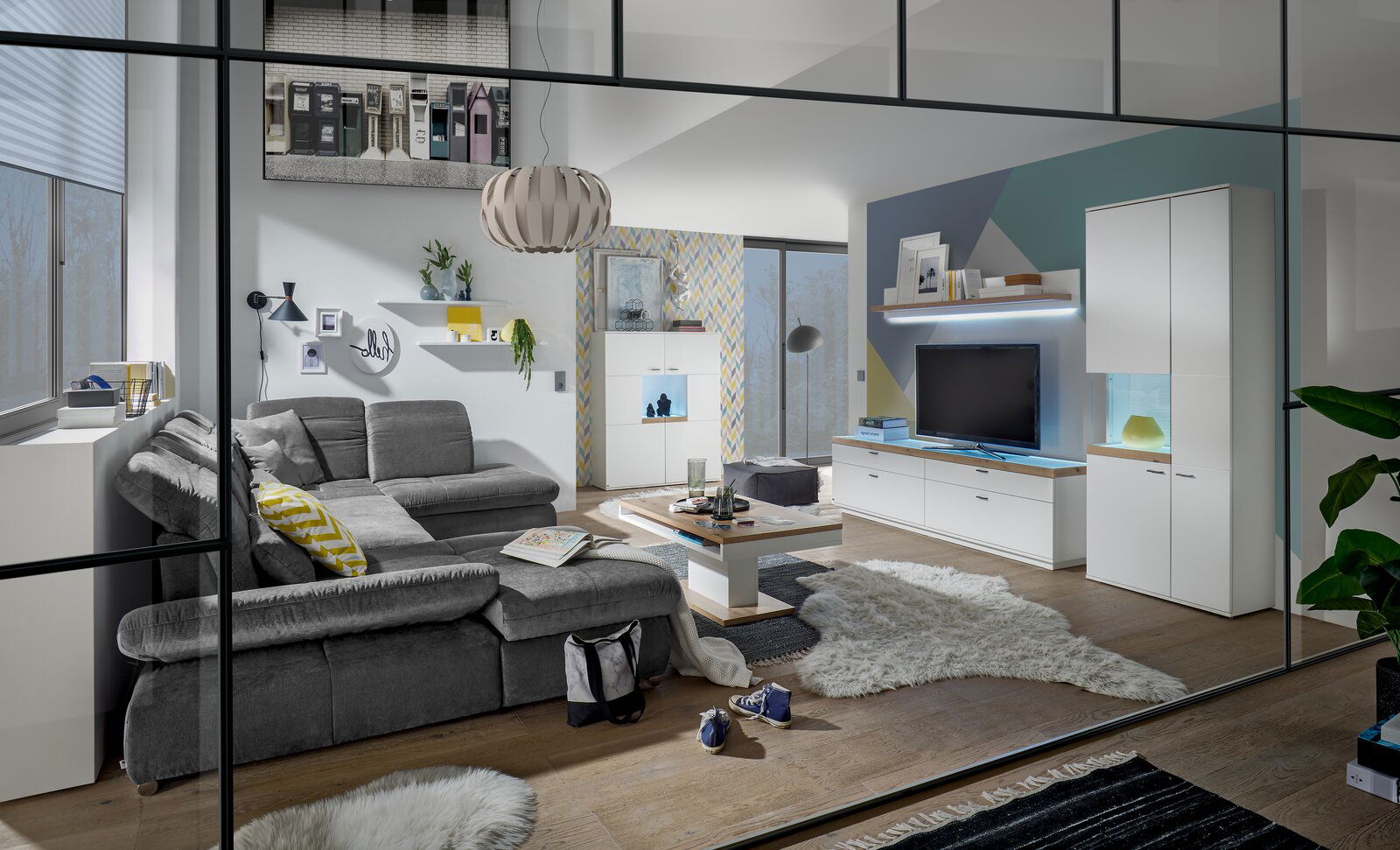 Moderne Wohnzimmeransicht mit grauem Sofa, Couchtisch und TV-Lowboard in einem stilvollen, hellen Raum.