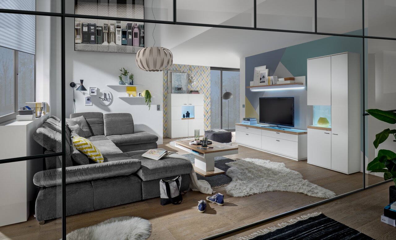 Set one by Musterring Vitrine Glasausschnitt links SET ONE LANCASTER Moderne Wohnzimmeransicht mit grauem Sofa, Couchtisch und TV-Lowboard in einem stilvollen, hellen Raum.