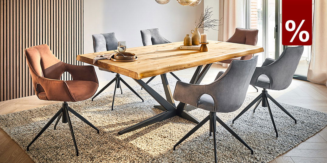 Modernes Esszimmer mit Holz-Tisch, Polsterstühlen und Designerlampe auf Teppich in heller Umgebung, %-Symbol