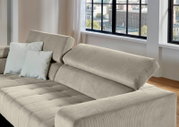 Beiges Cordsofa mit verstellbarer Rückenlehne und zwei hellen Kissen, gezeigt aus schräger Vorderansicht in einem hellen Wohnzimmer mit großen Fenstern.