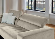 Beiges Cordsofa mit verstellbarer Rückenlehne und zwei hellen Kissen, gezeigt aus schräger Vorderansicht in einem hellen Wohnzimmer mit großen Fenstern.