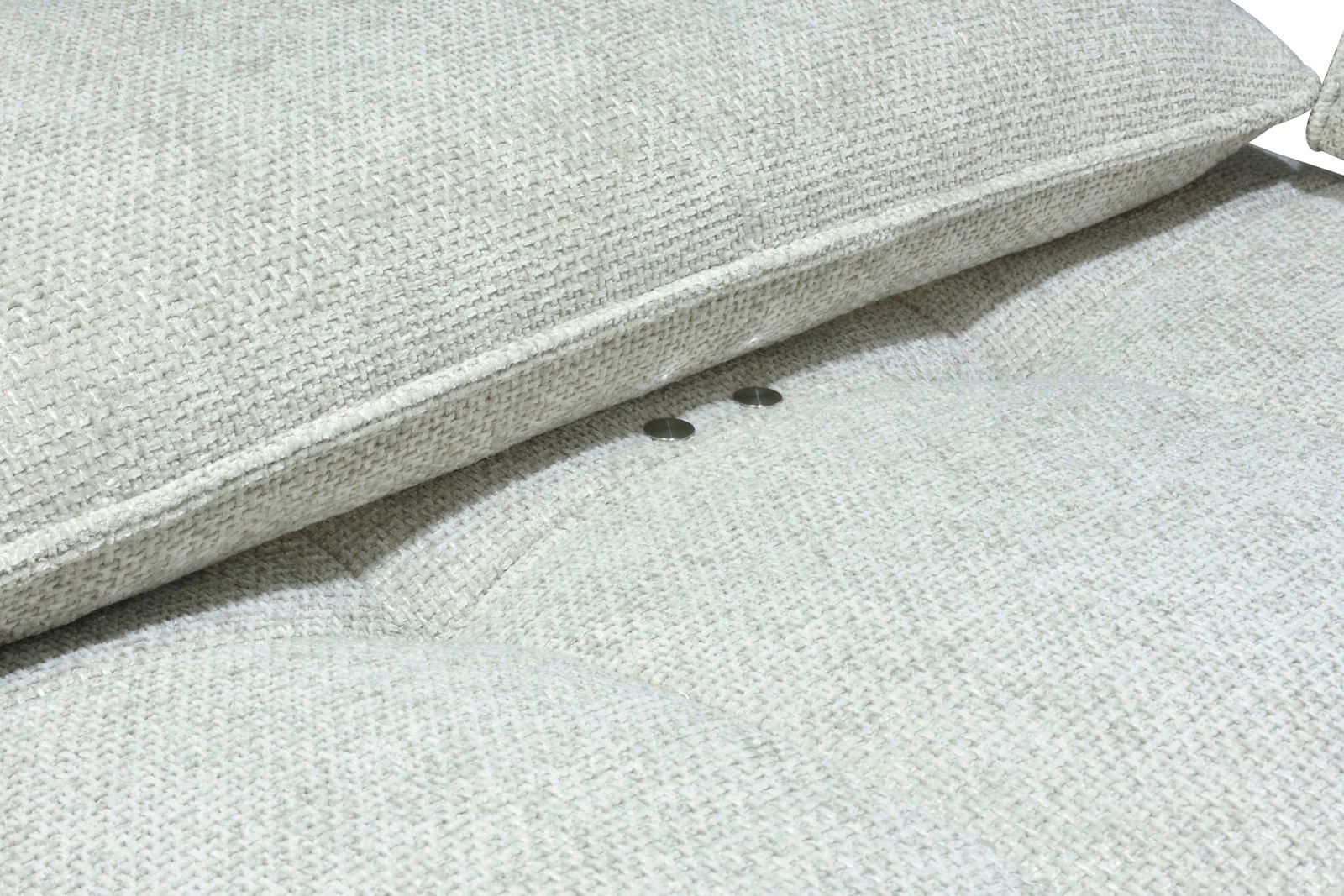Nahaufnahme eines hellgrauen Stoffsofas mit strukturierter Oberfläche und Knopfdetails.