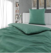 Grünliches Bettwäsche-Set mit Kissenbezug und Deckenbezug auf weißem Bett im modernen Schlafzimmer, Perspektive: frontale Ansicht mit leichtem Blick von oben.