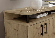 Nahaufnahme eines Sideboards aus Holz mit zwei Türen und schwarzen Griffen, dekoriert mit Büchern und einer Vase, aus seitlicher Perspektive.