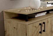 Close-up van een houten dressoir met twee deuren en zwarte handgrepen, versierd met boeken en een vaas, gezien vanuit een zijaanzicht.